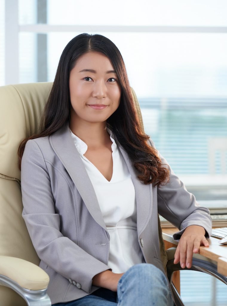 Smiling young confident business woman sitting in office